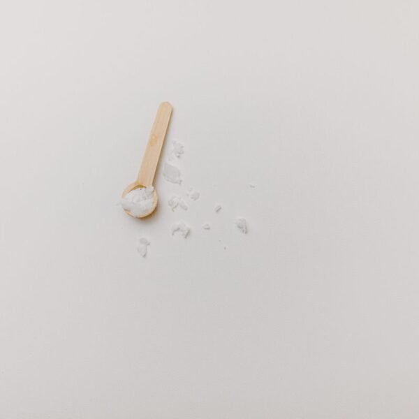Wooden cooking spoon with salt on a white background